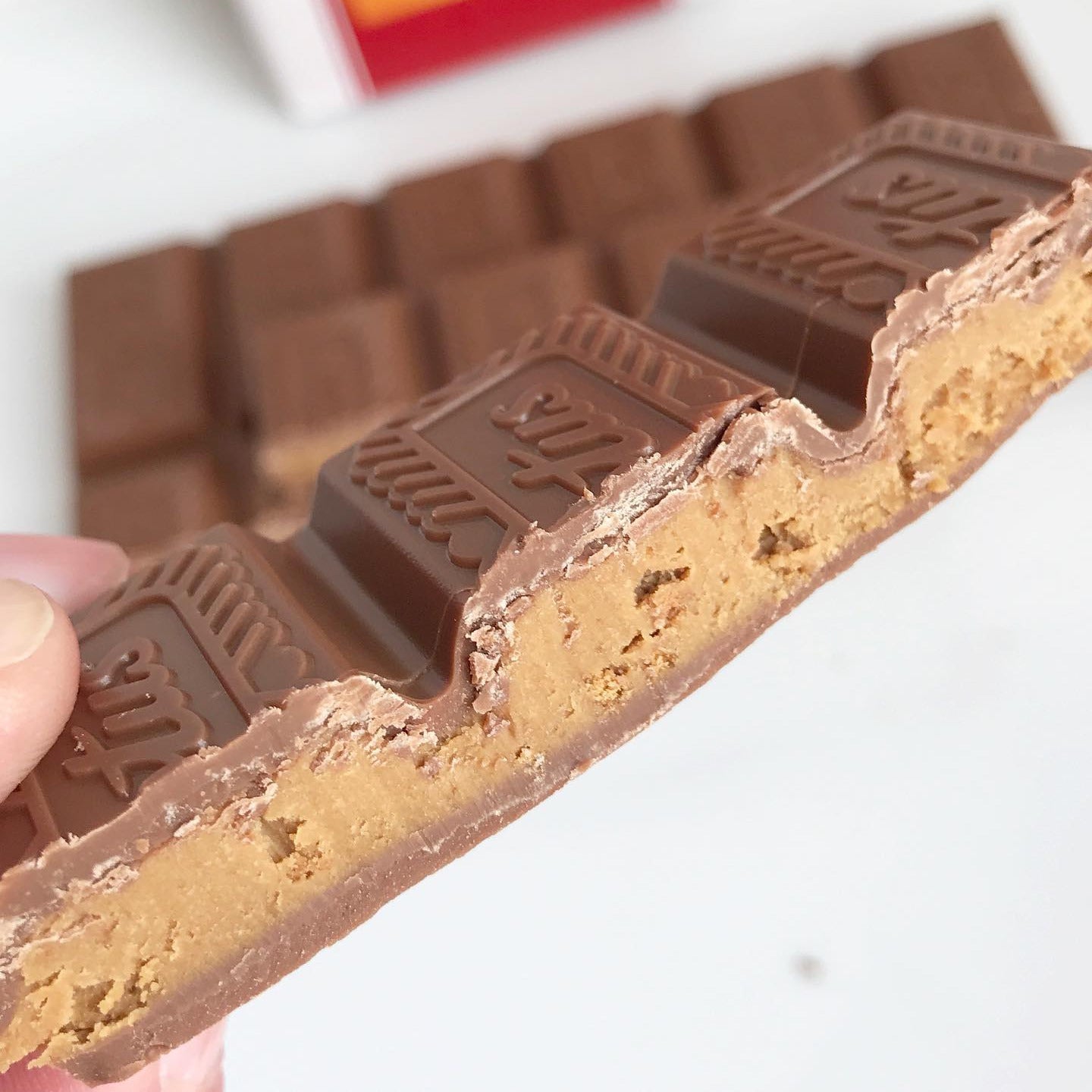 Close-up of a KitKat chocolate bar with a blurred red box in the background