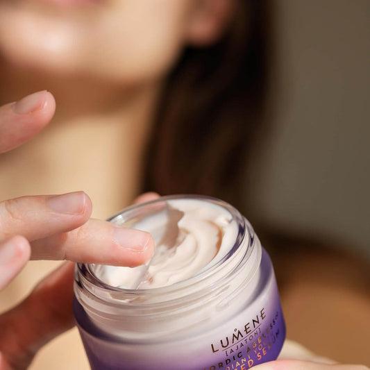 Person applying Lumene cream to their hand with a blurred background