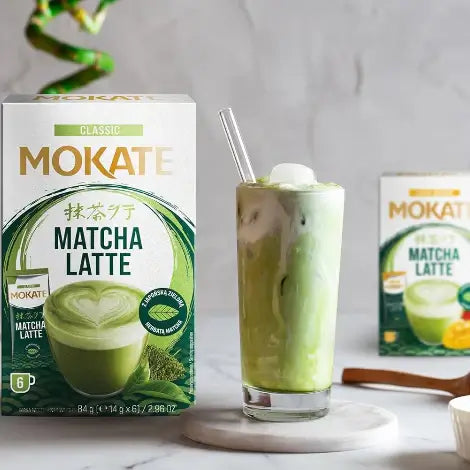 Mokate Classic Matcha Latte beverage served in a glass, showcasing smooth texture and rich green color, with packaging in the background.