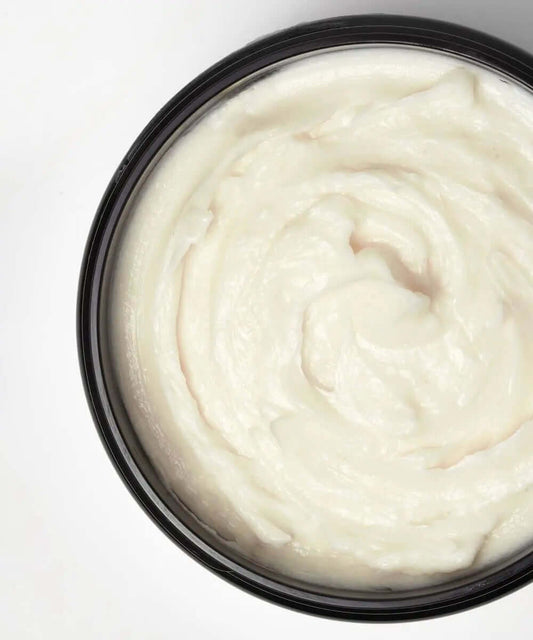 Top view of MIELLE ORGANICS Pomegranate & Honey Twisting SoufflÉ, creamy texture in a black jar.