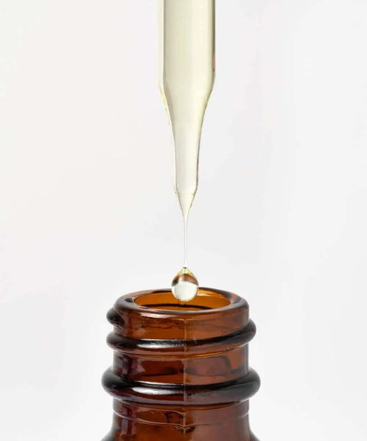 Dropper releasing MIELLE ORGANICS Rosemary Mint hair oil from amber bottle for hair strengthening.