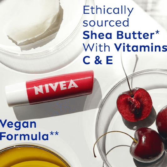 NIVEA Cherry Shine Lip Balm on a table with shea butter, cherries, and vitamin labels, emphasizing vegan-friendly formula.