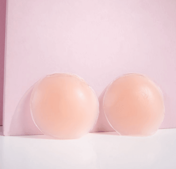 Brushworks silicone nipple covers shown on a pink background, smooth and discreet for braless wear.