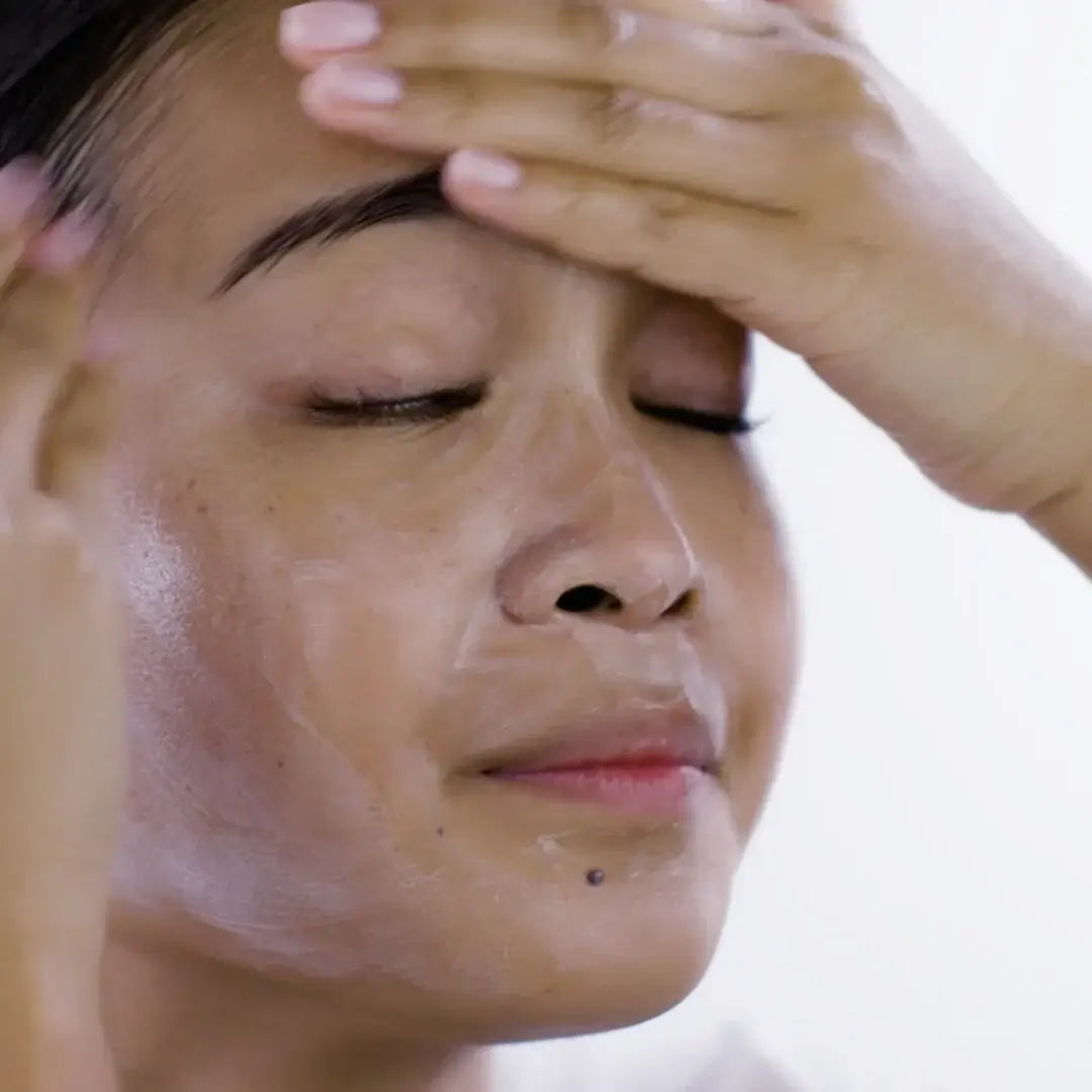 Person applying PIXI Glow Mud Cleanser on their face for a refreshing skincare routine.