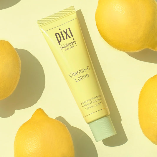 Pixi Vitamin-C Lotion tube surrounded by lemons on a yellow background
