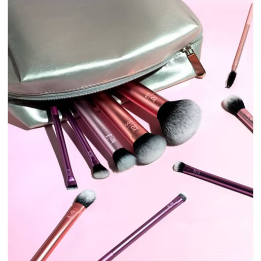 Real Techniques Makeup brushes with a silver pouch on a pink background