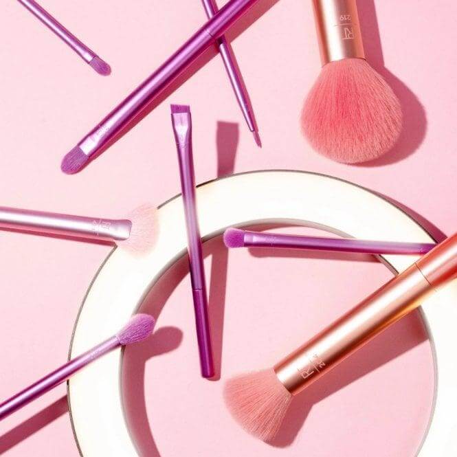 Real Techniques Insta Artist 9 Piece Makeup Brush Set with pink and purple brushes on a light background.