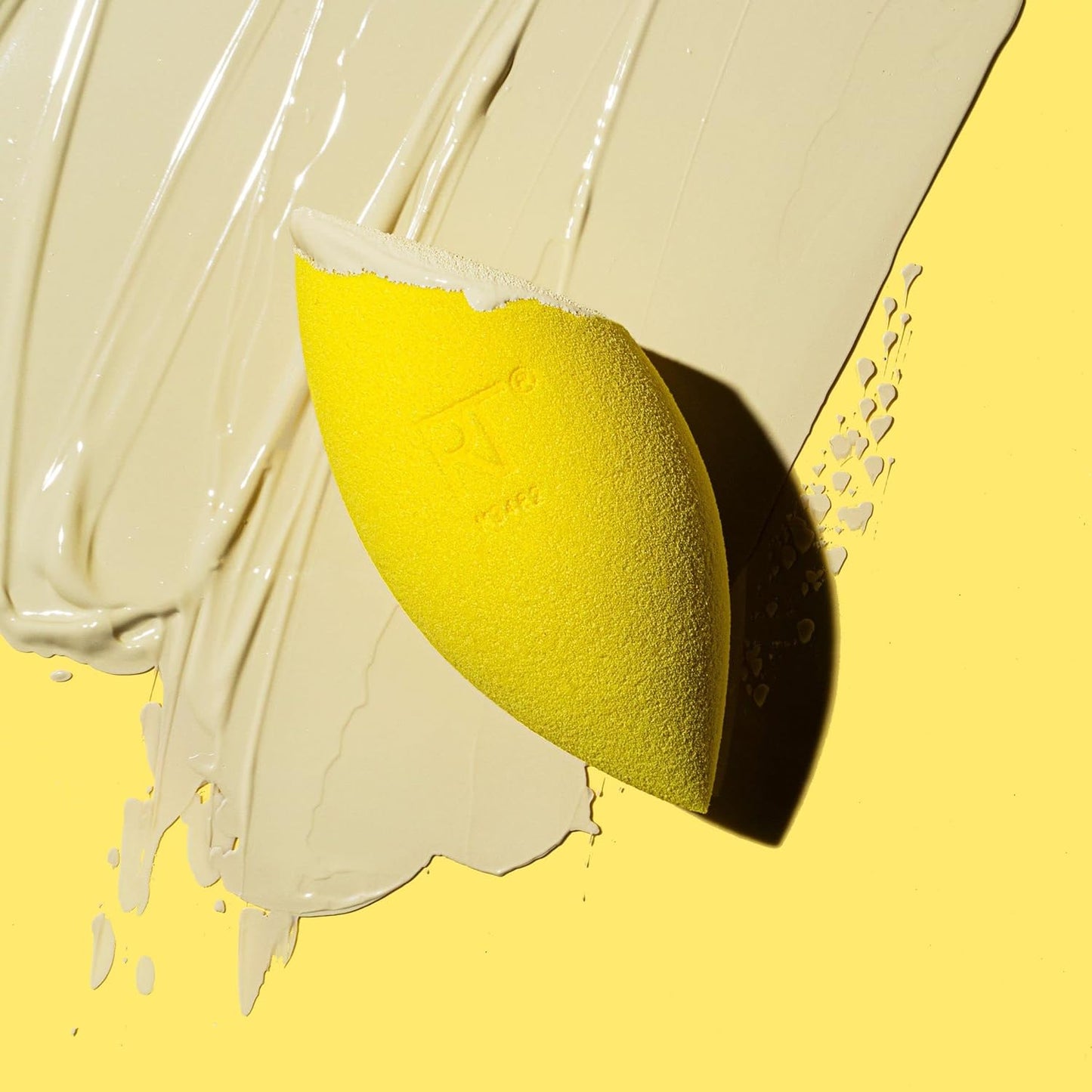 Yellow makeup sponge on a yellow background with white paint strokes