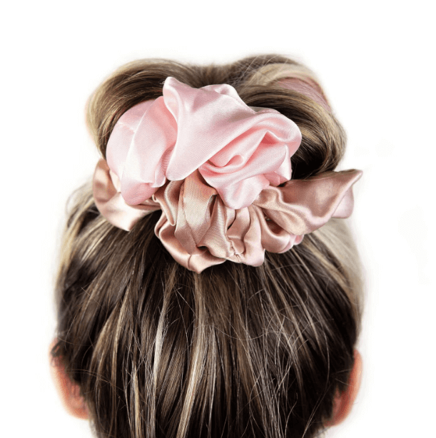 Brushworks Heatless Curling Scrunchie in pink satin, styled in a hair bun for heat-free curls and smooth finish.