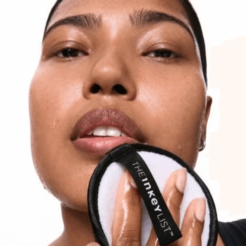 Close-up of a woman using THE INKEY LIST Reusable Cleansing Pad for an eco-friendly skincare routine.