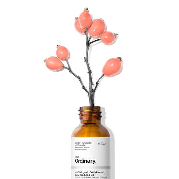 The Ordinary 100% Organic Cold-Pressed Rose Hip Seed Oil bottle with pink rose hip berries.