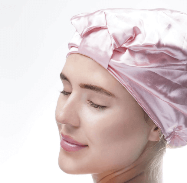 Model wearing Brushworks Satin Hair Turban in pink to promote frizz-free hair and protect curls overnight.