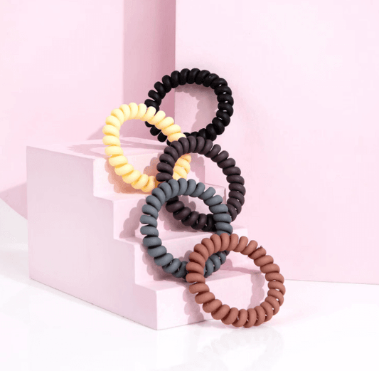 Brushworks Wonder Bobble - Natural, five non-soaking spiral hair ties in assorted colors on pink steps.