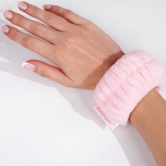 Close-up of a pink Brushworks microfibre wrist wash band on a hand, designed for a mess-free face washing experience.