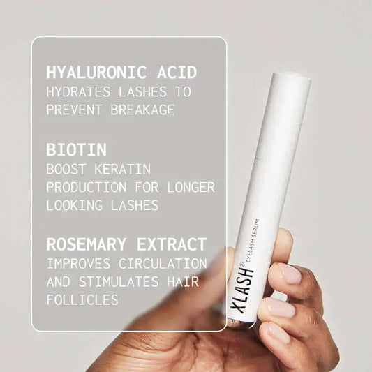 Hand holding a white lash serum with text about ingredients on a gray background