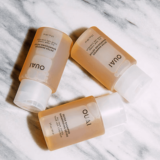 OUAI Detox Shampoo bottles on marble surface, featuring apple cider vinegar for deep cleansing and a rose fragrance.
