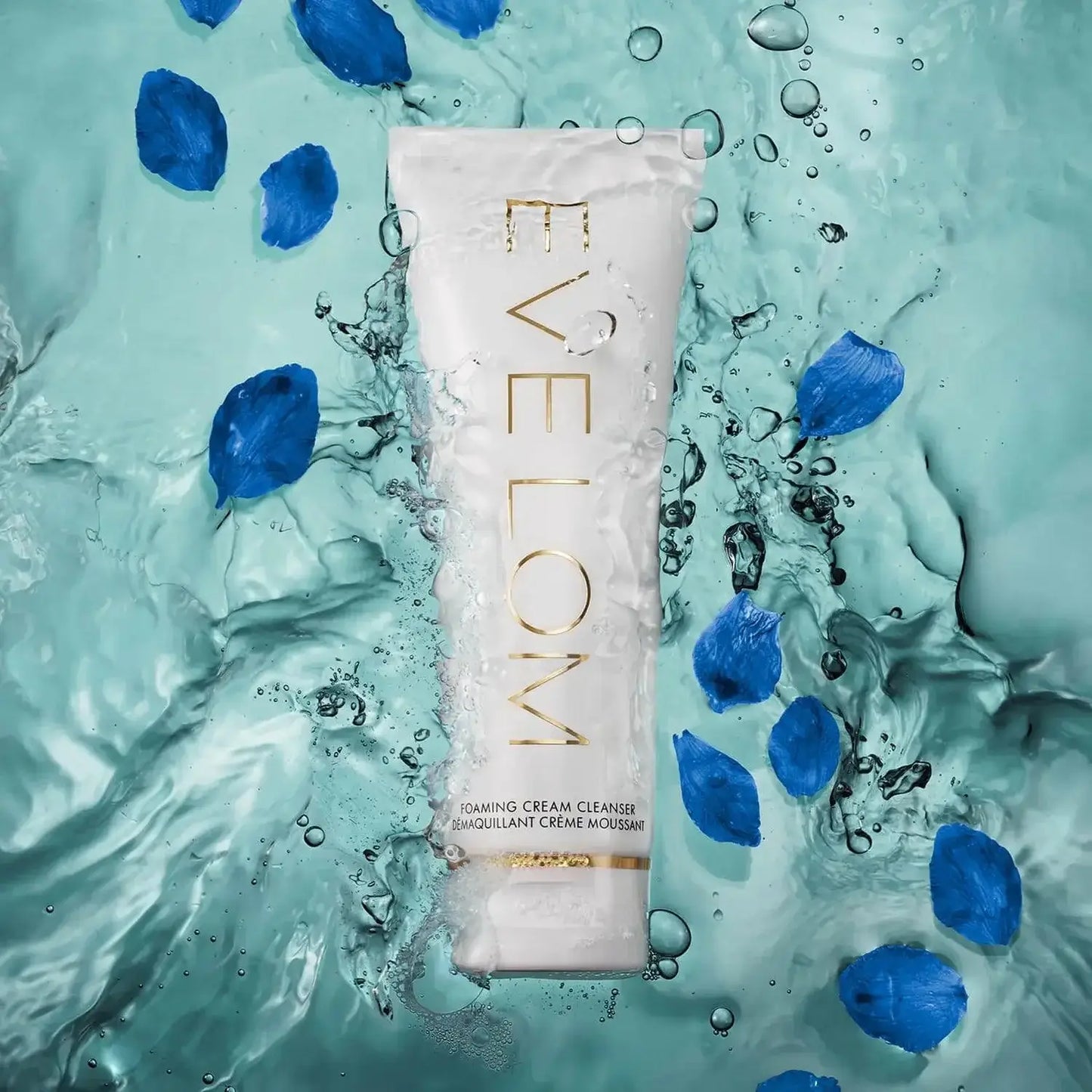 Eve Lom Foaming Cream Cleanser 120ml tube immersed in water with blue petals, promoting fresh and luminous skin.
