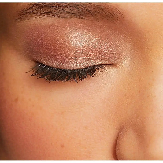 Close-up of a closed eye with shimmering rose gold eyeshadow applied, showcasing a soft, elegant look.