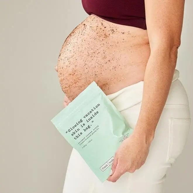 Pregnant woman holding Frank body Coconut Coffee Scrub bag with scrub on her belly, promoting glowing skin.