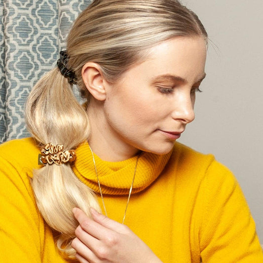 Woman wearing invisibobble Sprunchie Slim True Golden hair scrunchies in sleek ponytail, showcasing elegant design.