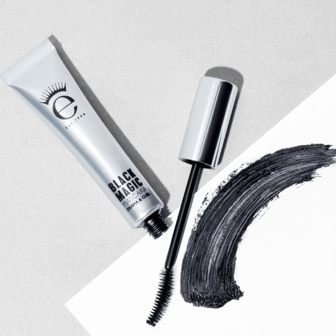 Eyeko Black Magic Mascara with applicator next to a bold stroke of black mascara on a light background.