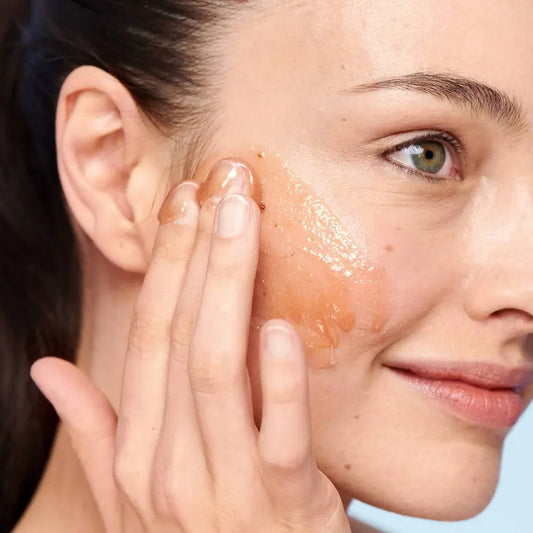 Woman applying Fresh Sugar Strawberry Exfoliating Face Wash on her cheek, showcasing gentle exfoliation and hydration.