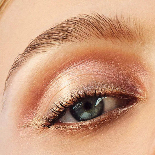 Close-up of an eye showcasing shimmery golden pink cream eyeshadow for a vibrant look.