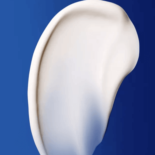 Close-up of Augustinus Bader The Rich Cream's luxurious texture on a blue background.