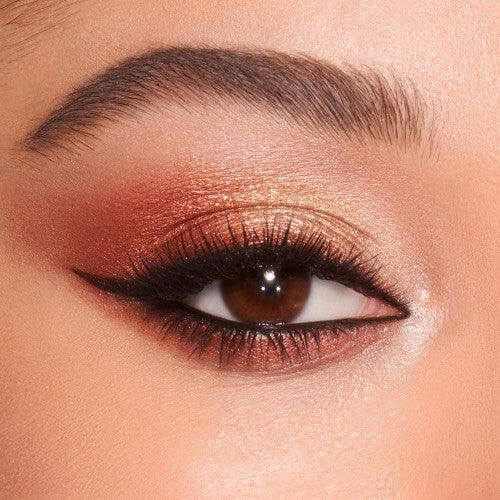 Close-up of an eye featuring bronze and copper eyeshadow with dramatic eyeliner, showcasing a glamorous makeup look.