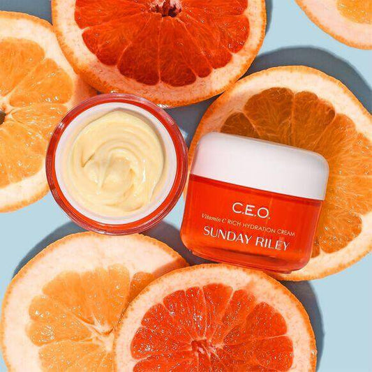 Sunday Riley CEO Vitamin C Rich Hydration Cream jar surrounded by orange slices, showcasing vibrant skincare.