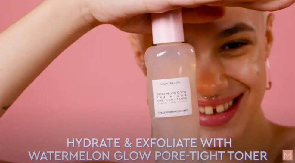 Smiling person holding Glow Recipe Watermelon Glow PHA + BHA Pore-Tight Toner, promoting hydration and exfoliation.