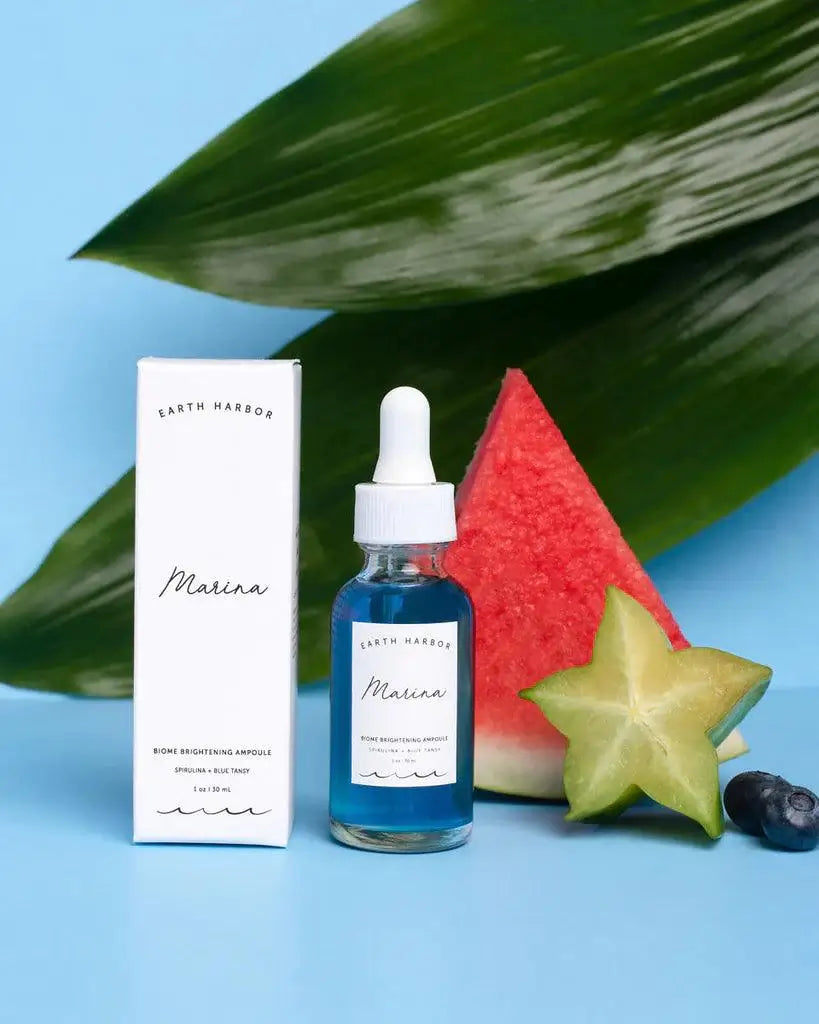 Earth Harbor Marina Biome Brightening Ampoule with packaging, watermelon, and starfruit on a blue background.