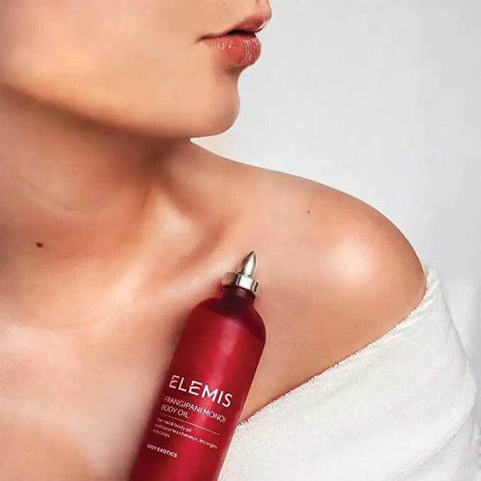 Woman applying Elemis Frangipani Monoi Body Oil on shoulder for hydration and moisturization