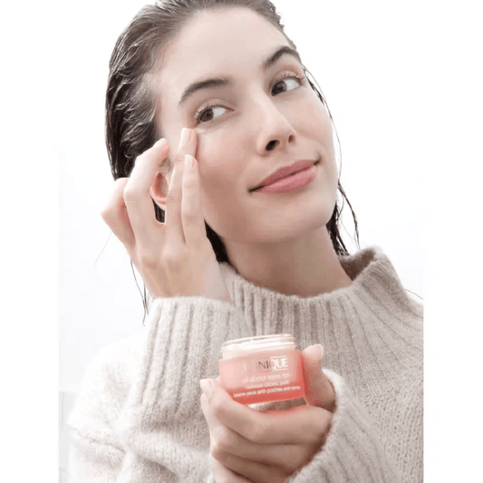 Woman applying Clinique All About Eyes eye cream to minimize puffiness and dark circles.