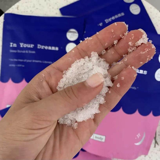 Close-up of Frank Body In Your Dreams Scrub and Soak salt in hand, showcasing relaxation and bath product benefits.