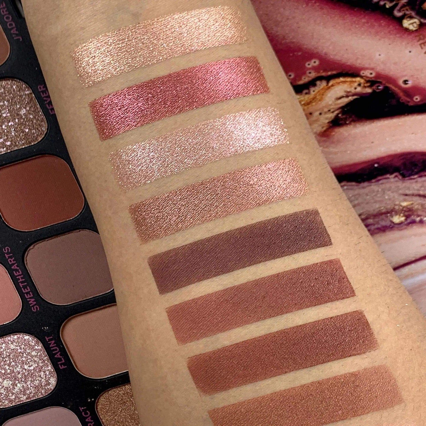 Swatches of Forever Flawless Allure Eye Shadow Palette showcasing 18 matte and shimmer shades on a model's arm.