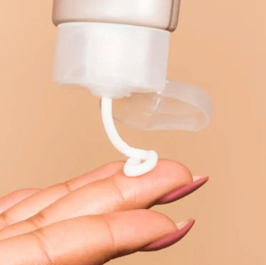 A hand dispensing The Ordinary Natural Moisturising Factors + HA from a tube for deep skin hydration.