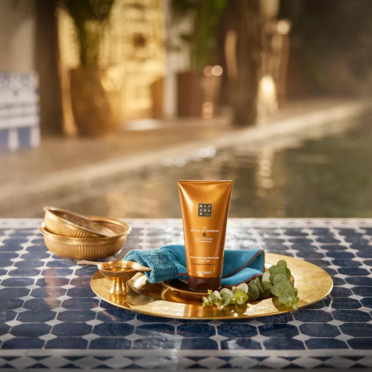 RITUALS The Ritual of Hammam Black Soap on a decorative plate near a pool, showcasing luxurious skincare.