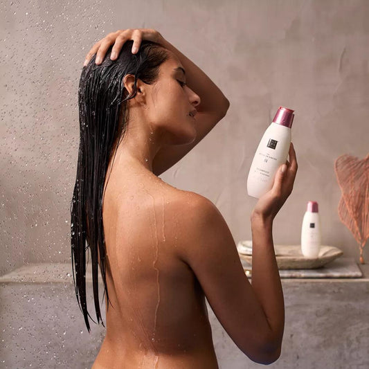 Woman in shower using RITUALS The Ritual of Sakura Conditioner for smooth, shiny hair.