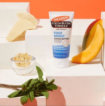 Palmer's Cocoa Butter Formula Foot Magic 60g cream with Cocoa Butter and Peppermint Oil on display with mango and mint.