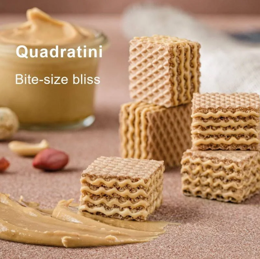 Loacker Quadratini Peanut Butter wafer cookies stacked beside creamy peanut butter, showcasing bite-sized crunchy snacks.