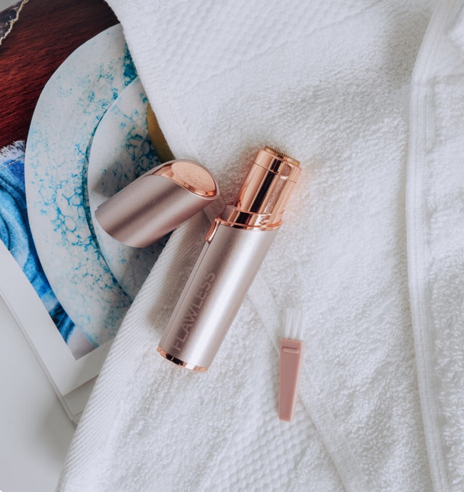 Rose gold and silver skincare device on a white towel with a blurred background
