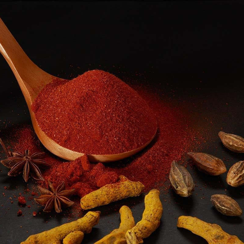 Rajah Tandoori Masala blend with spices on a wooden spoon, enhancing authentic Indian dishes.