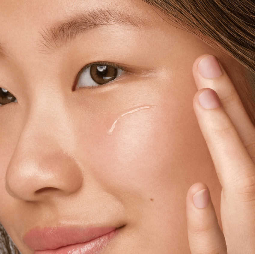Woman applying Kiehl's Clearly Corrective Dark Spot Solution to her cheek for an even skin tone.