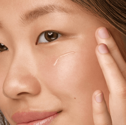 Woman applying Kiehl's Clearly Corrective Dark Spot Solution to her cheek for an even skin tone.