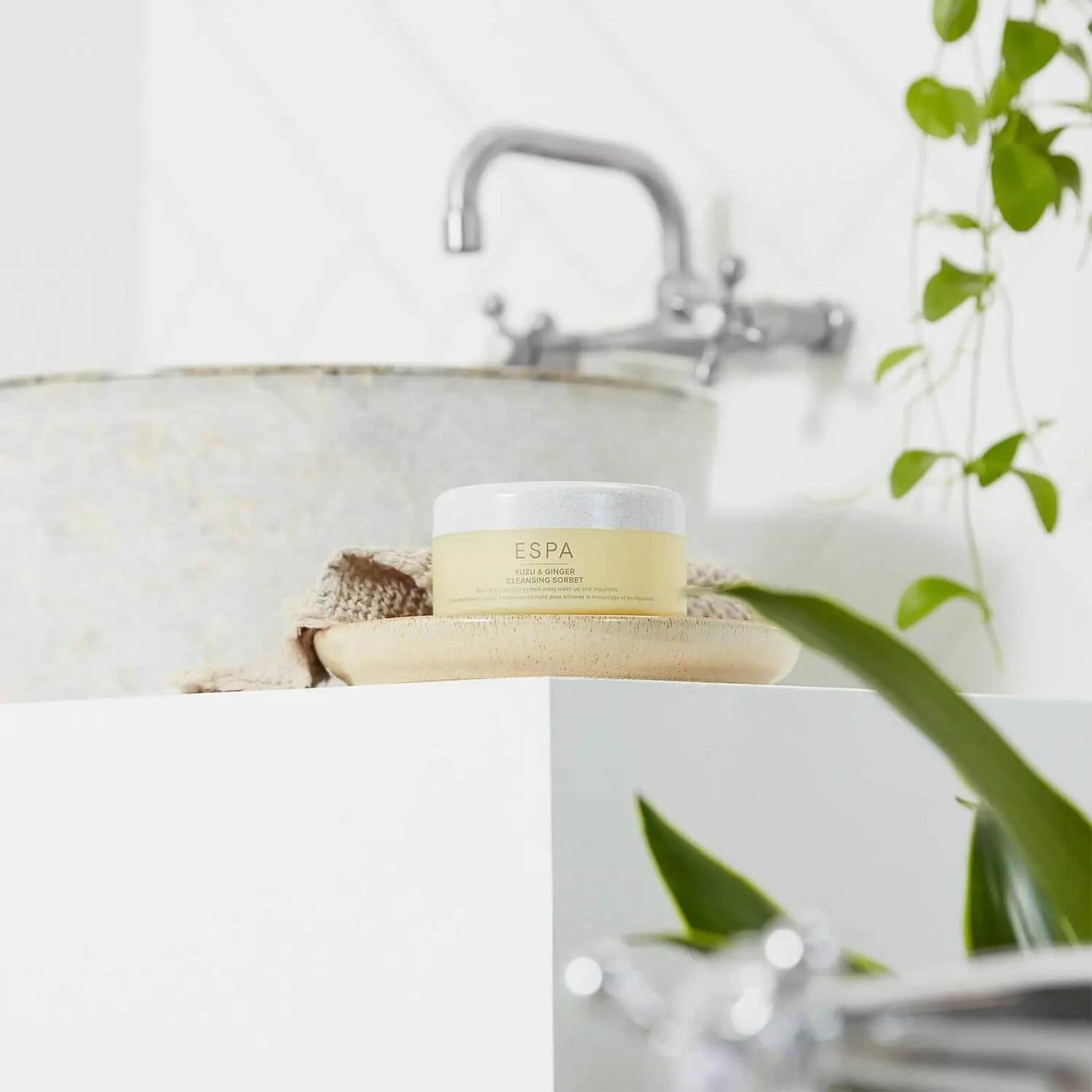 Espa product on a bathroom counter with a sink and plant in the background