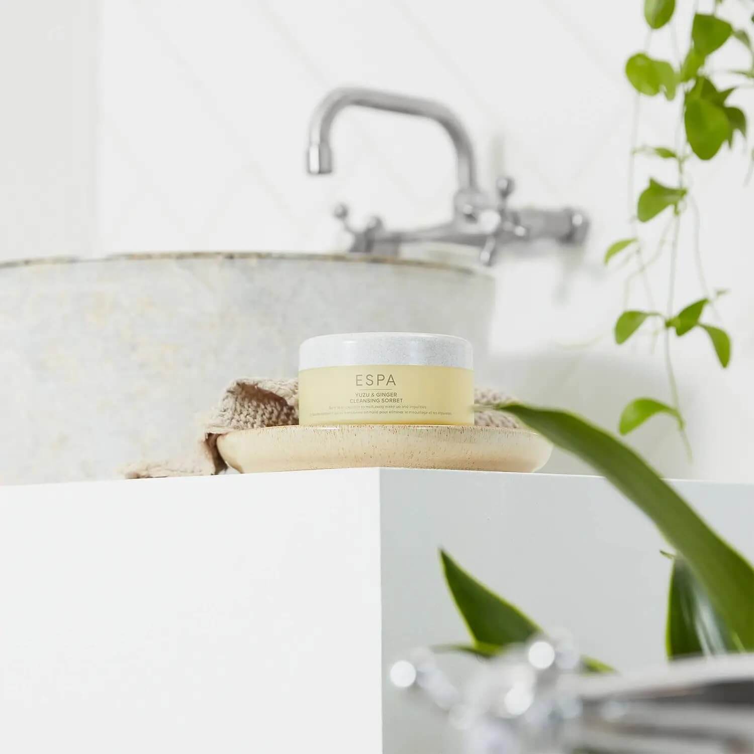 Espa product on a bathroom counter with a sink and plant in the background