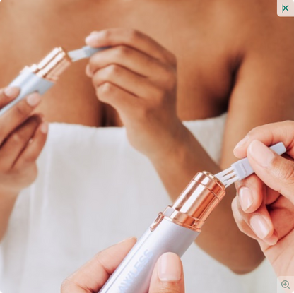 Close-up of hands using a white and rose gold skincare device on a blurred background