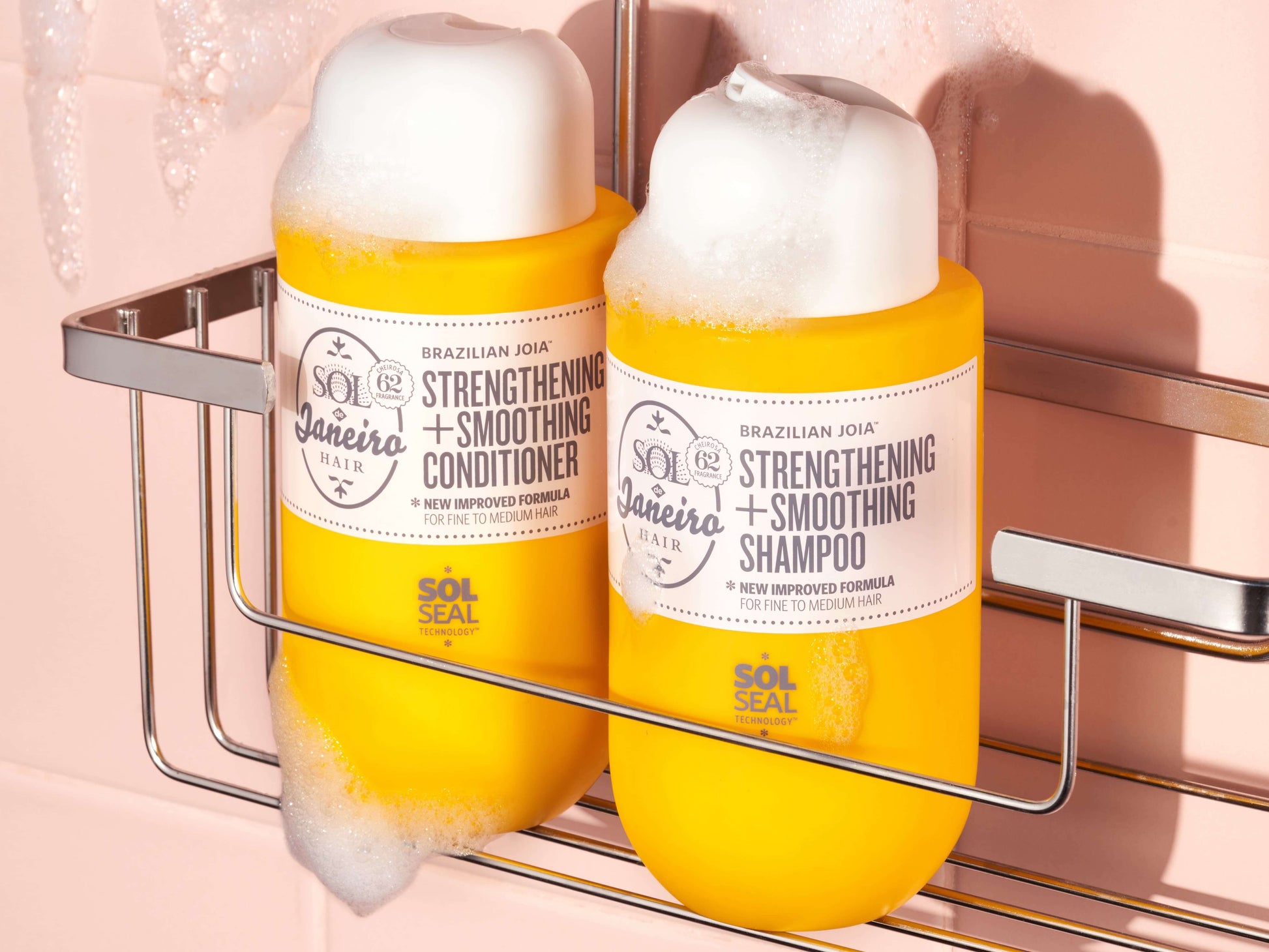 Sol de Janeiro Brazilian Joia Strengthening and Smoothing Shampoo and Conditioner in a shower rack with bubbles.