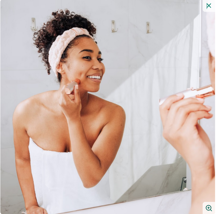 Woman applying makeup in front of a mirror